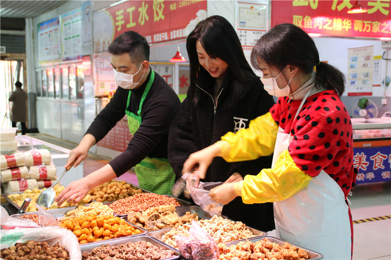 图为居民在农贸市场摊位上购买食品.图片来源:何娟